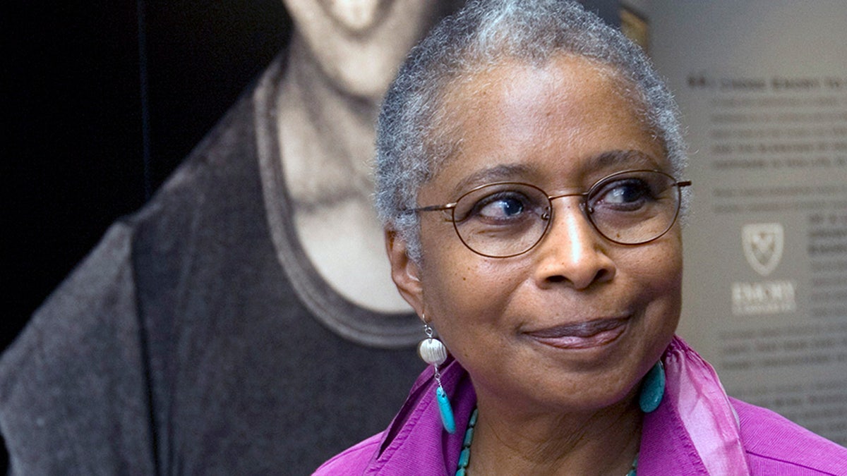 FILE - In this April 23, 2009 file photo, Alice Walker stands in front of a picture of herself from 1974 as she tours her archives at Emory University, in Atlanta. (AP Photo/John Amis, File)