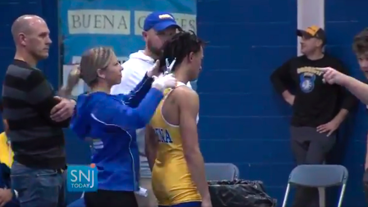 Buena Regional High School wrestler Andrew Johnson getting his hair cut courtside minutes before his match in Buena, N.J., after a referee told Johnson he would forfeit his bout if he didn’t have his dreadlocks cut off. (Michael Frankel/SNJTODAY.COM viavAP)