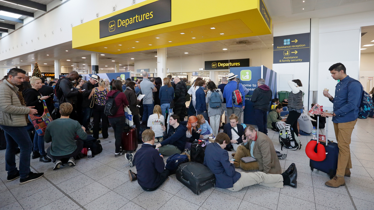 People wait outside the departures gate at Gatwick airport, near London, as the airport remains closed with incoming flights delayed or diverted to other airports, after drones were spotted over the airfield last night and this morning, Thursday, Dec. 20, 2018. London's Gatwick Airport remained shut during the busy holiday period Thursday while police and airport officials investigate reports that drones were flying in the area of the airfield.