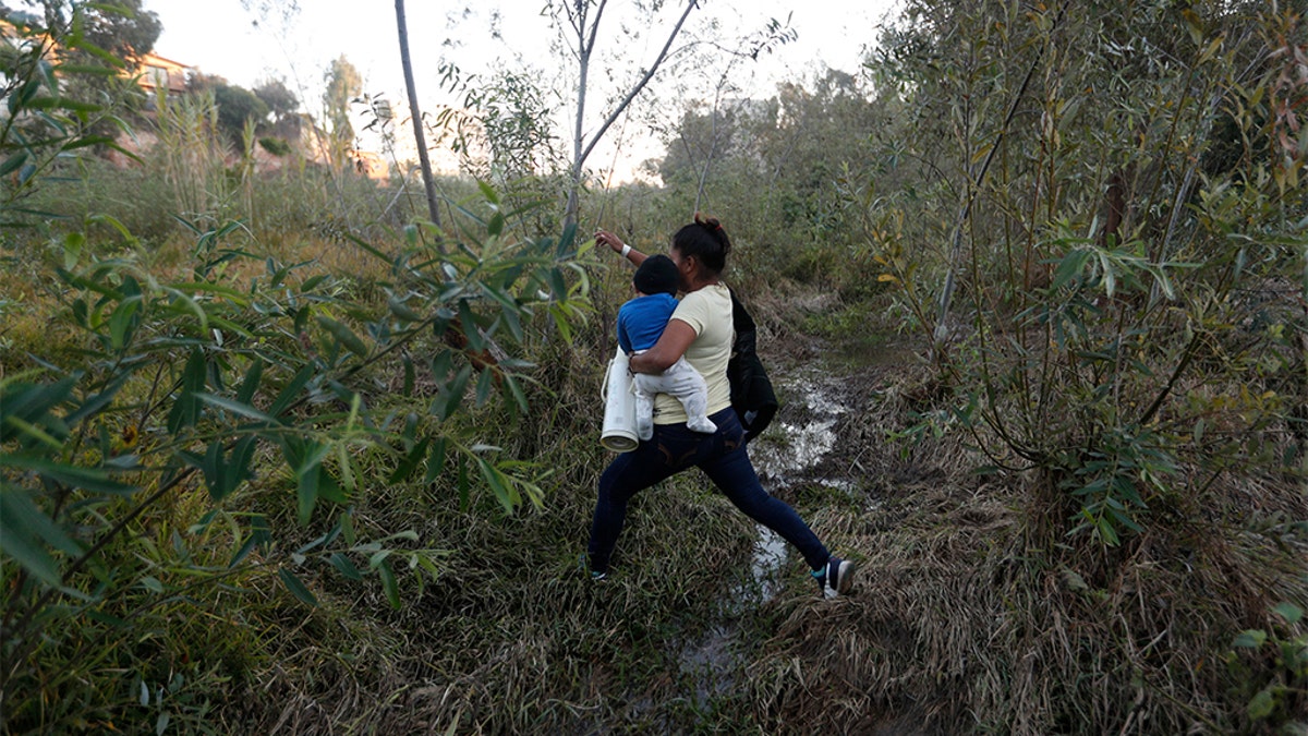 Yesenia Martinez, 24, carrying her eight-month-old son Daniel as she looked for a place to cross the U.S. border wall. (AP Photo/Rebecca Blackwell)