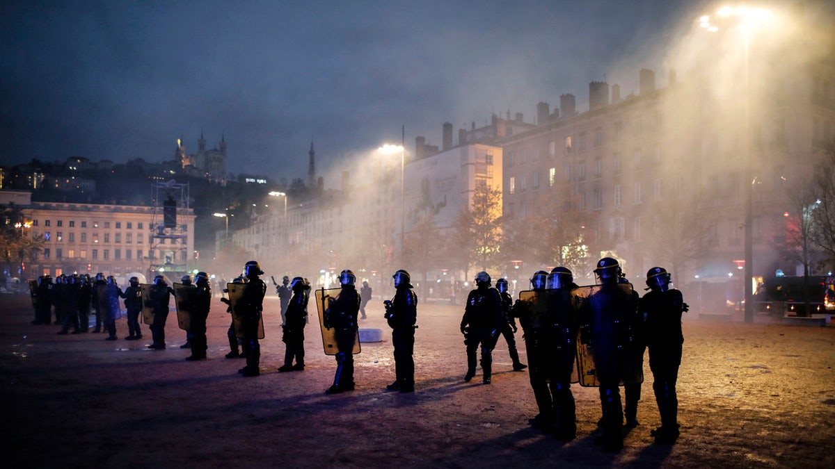 Police officers face demonstrators in Lyon, central France, Saturday, Dec. 8, 2018. The grassroots movement began as resistance against a rise in taxes for diesel and gasoline, but quickly expanded to encompass frustration at stagnant incomes and the growing cost of living. (AP Photo/Laurent Cipriani)