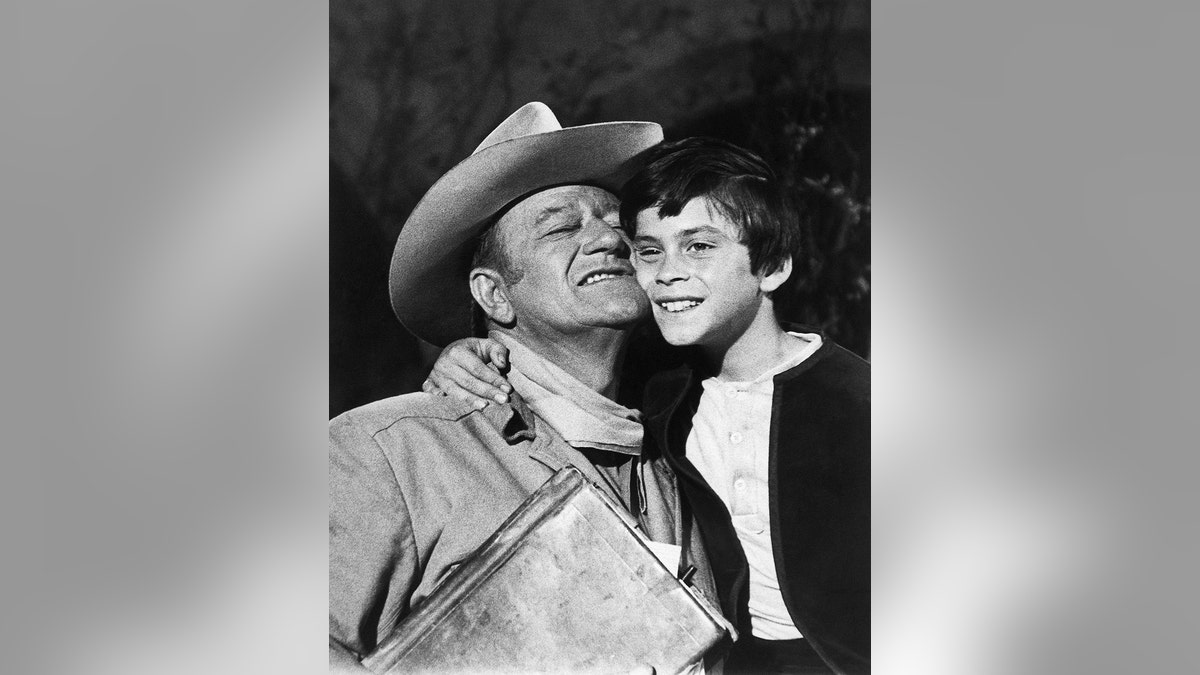 Ethan Wayne, 8, gets a hug from dad, John Wayne, after filming a shootout scene with outlaws in 'The Million Dollar Kidnapping.'