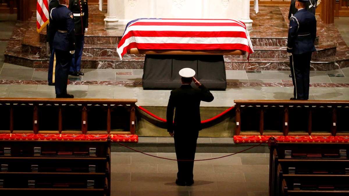 A member of the military pays his respects to the flag-draped casket of former President George H.W. Bush at St. Martin's Episcopal Church Wednesday, Dec. 5, 2018, in Houston. (AP Photo/Mark Humphrey)