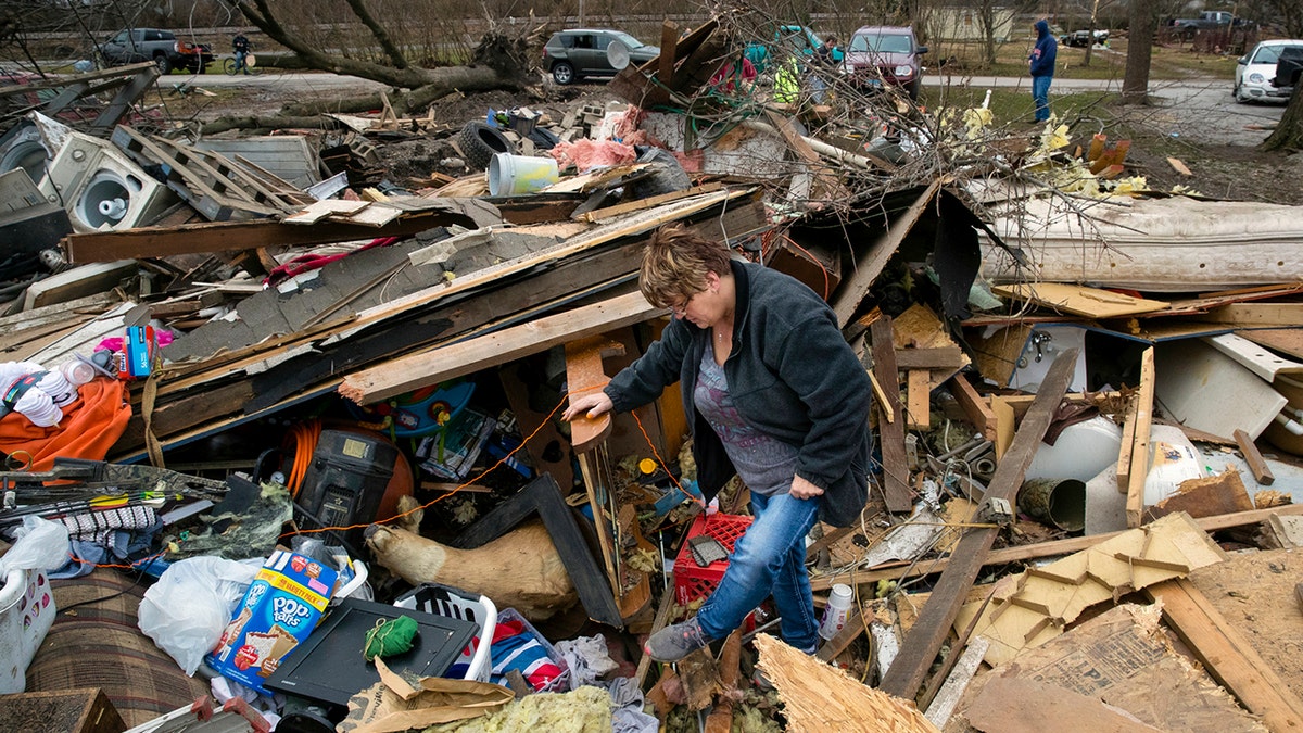 Joyce Morrissey sorting through the debris of her nephew Stephen Tirpak's house in Taylorville, Ill., Sunday. The National Weather Service said multiple tornadoes touched down in central Illinois, damaging dozens of structures and injuring multiple people. (Ted Schurter/The State Journal-Register via AP)