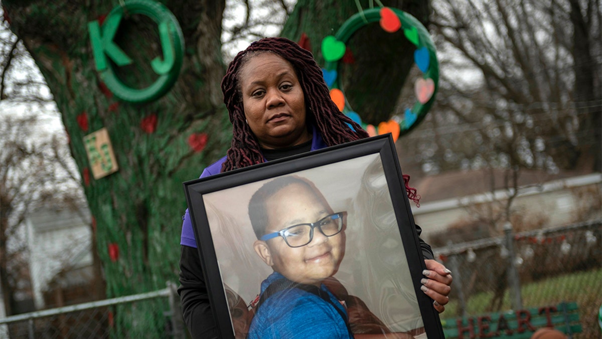 LaSondra Singleton holding a photo of her son Kenneth Gross Jr. while standing in front of a tree that was decorated in the child's honor at her Warren, Mich., home. Kenneth died at age 12 waiting for a donor heart that failed due to complications from cancer. (David Guralnick/Detroit News via AP)
