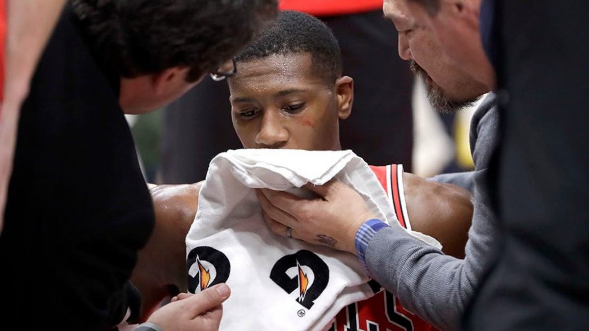Chicago Bulls' Kris Dunn is treated by the medical staff after hitting his face on the floor after a dunk.