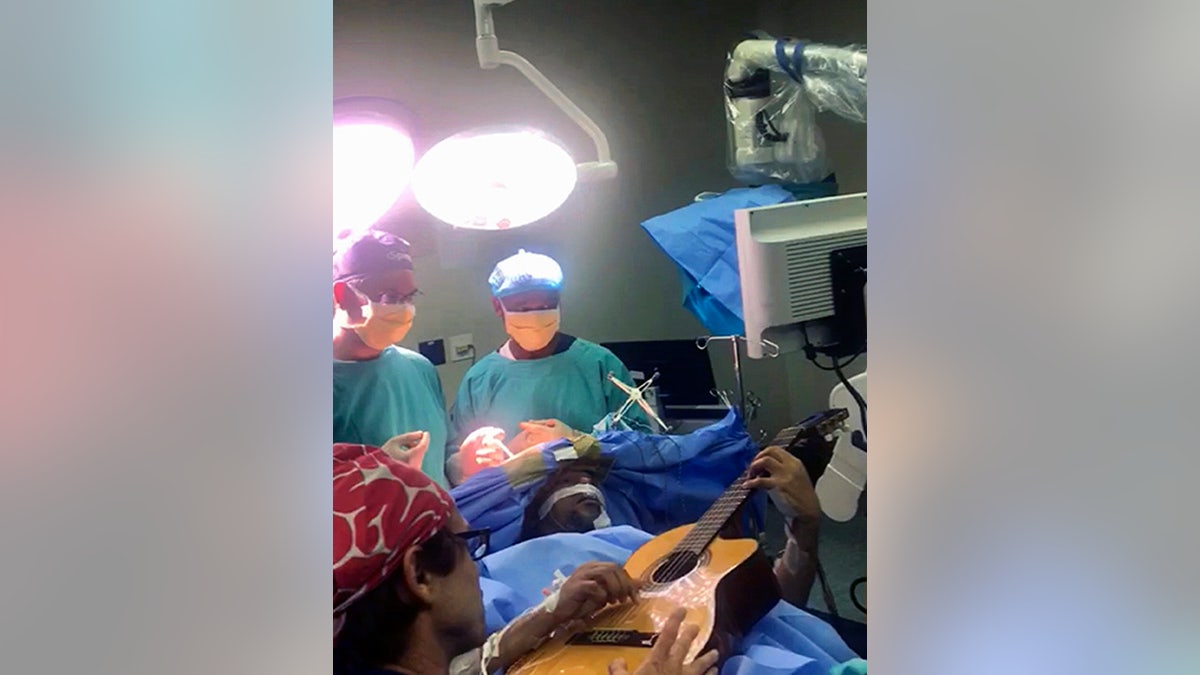In this photo supplied by the Department of Neurosurgery, Inkosi Albert Luthuli Central Hospital on Saturday, Dec. 22, 2018, taken earlier this month during surgery South African musician, Musa Manzini, plays a guitar during brain surgery. (OnyekaValentine Ilorah for Department of Neurosurgery, Inks Albert Luthuli Central Hospital, via AP)