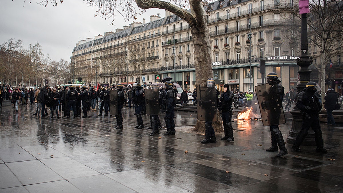 The student protesters marched through Paris to the Republic Square, where they recreated the arrest scene while being surrounded by police officers wearing riot gear.