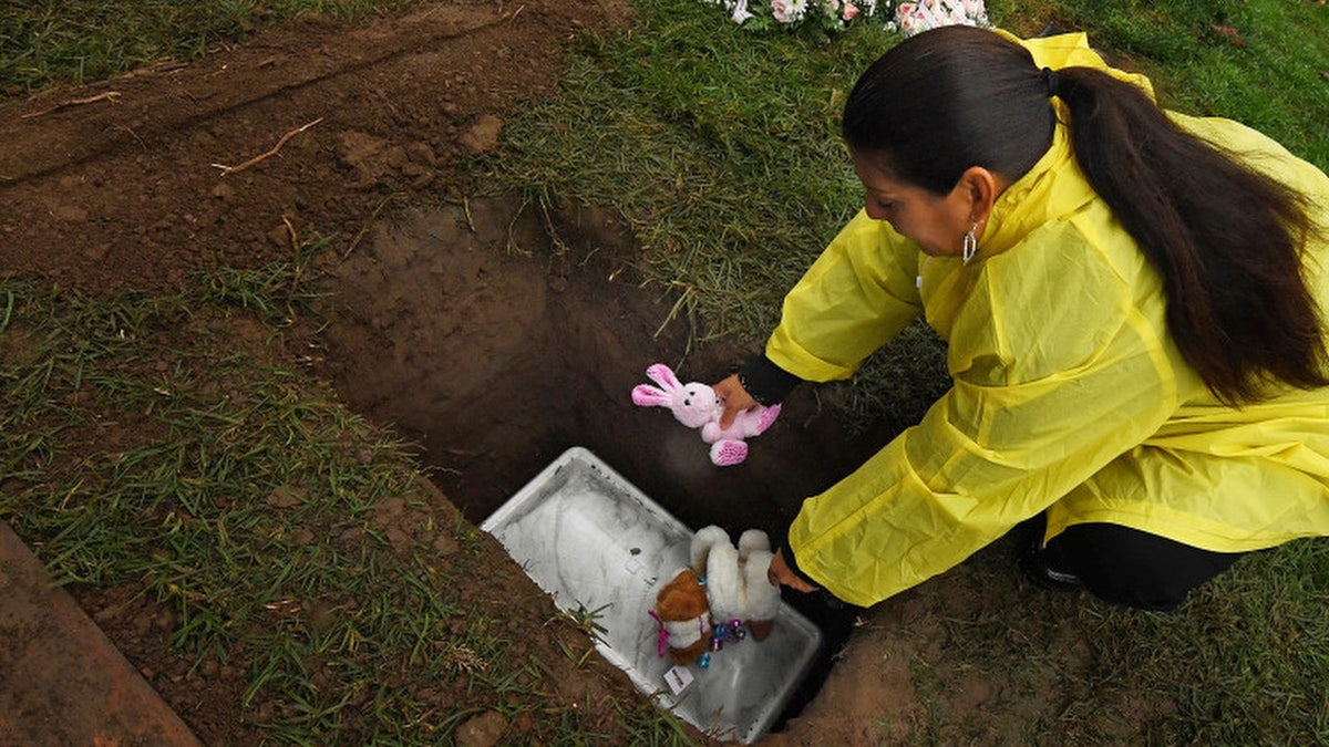 Monica Montejano, from Corona, Calif., places stuffed animals atop the grave of Baby Jane Doe at Sunnyslope Cemetery in Corona, Calif.. Police are still searching for the person or persons responsible.