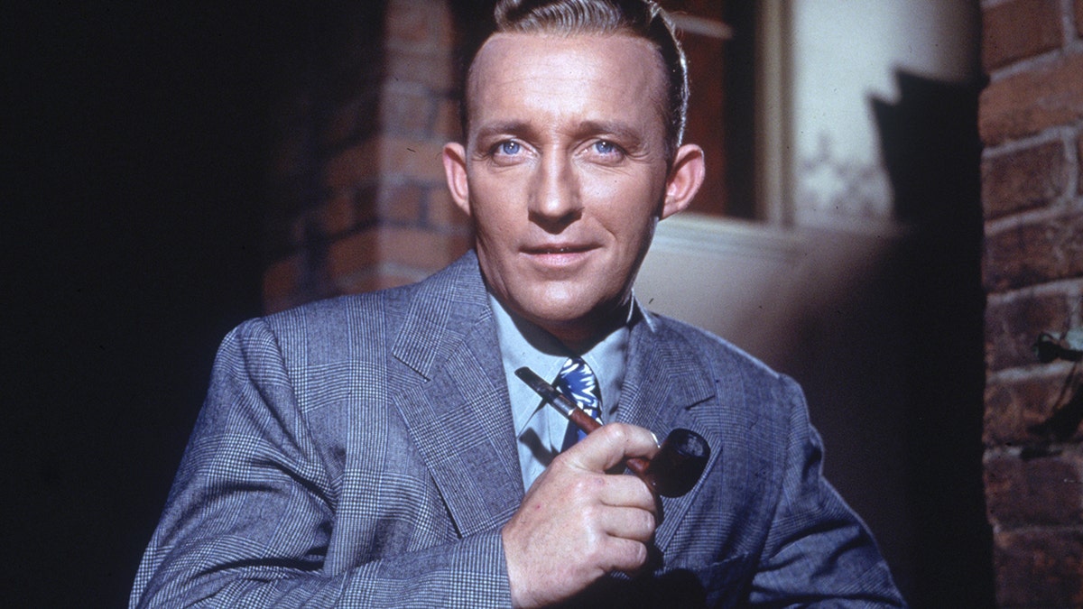 American actor and singer Bing Crosby poses for a portrait holding a pipe in his hand in 1948.