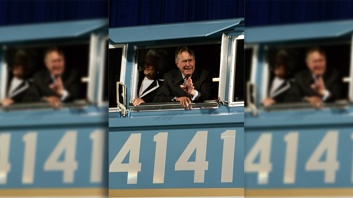 Former President George H.W. Bush and his wife Barbara wave out the window of a locomotive numbered 4141 on Oct. 18, 2005, at Texas A&amp;M in College Station, Texas. 
