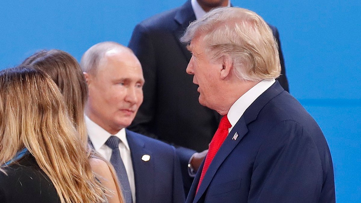 Russia's President Vladimir Putin, left, watches President Donald Trump, right, walk past him as they gather for the group photo at the start of the G20 summit in Buenos Aires, Argentina.