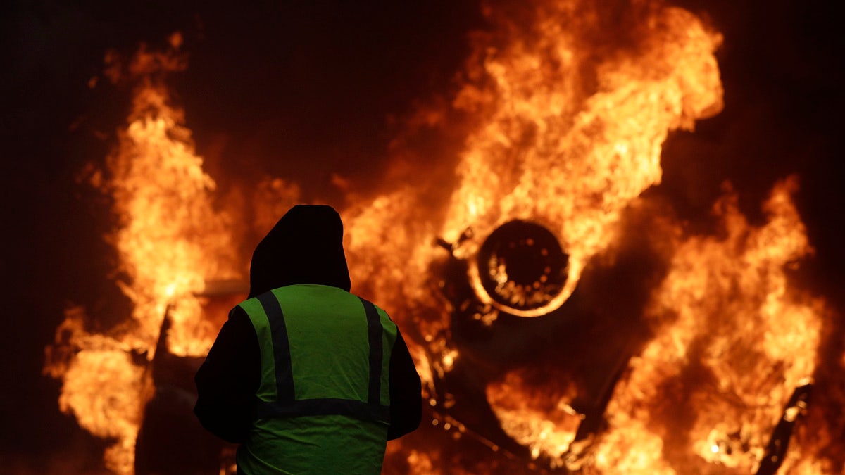 A demonstrator watches a burning car near the Champs-Elysees avenue during a demonstration Saturday in Paris. 