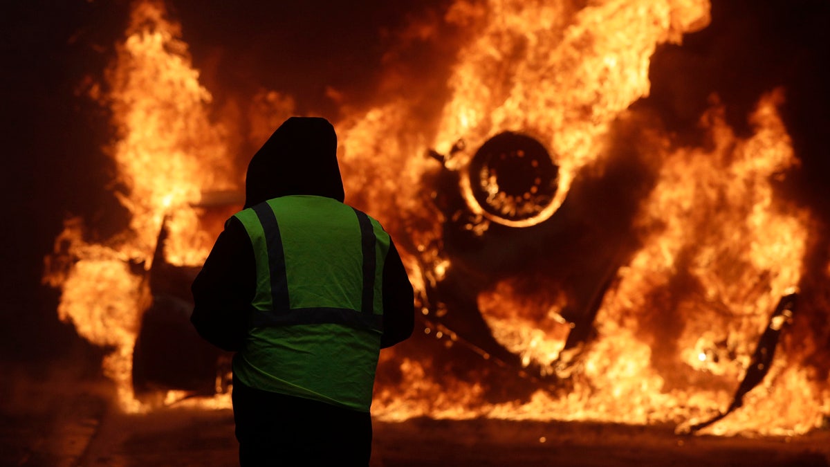 A demonstrator watches a burning car near the Champs-Elysees avenue during a demonstration Saturday in Paris.