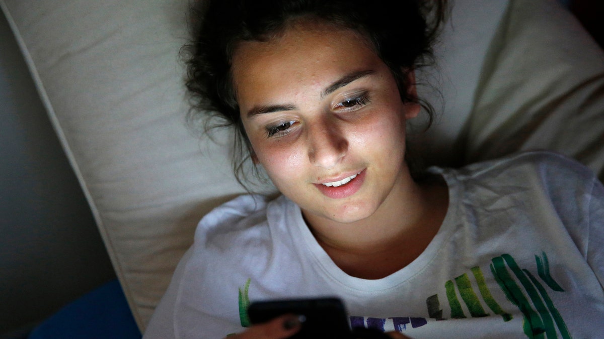 teen using cell phone in dark room