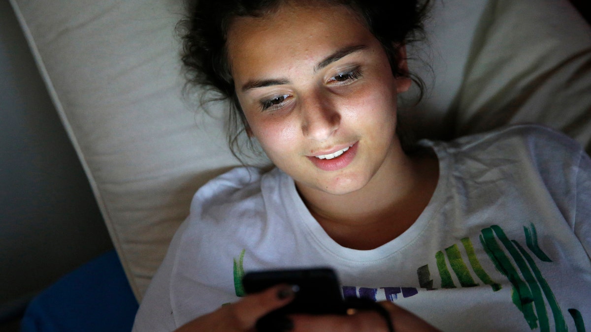 teen using cell phone in dark room