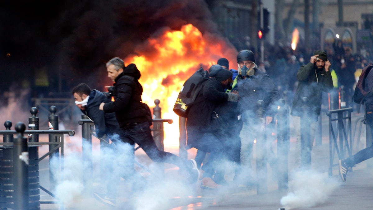 People run away from a burning car during clashes, Saturday, Dec. 8, 2018 in Marseille, southern France. (AP Photo/Claude Paris)