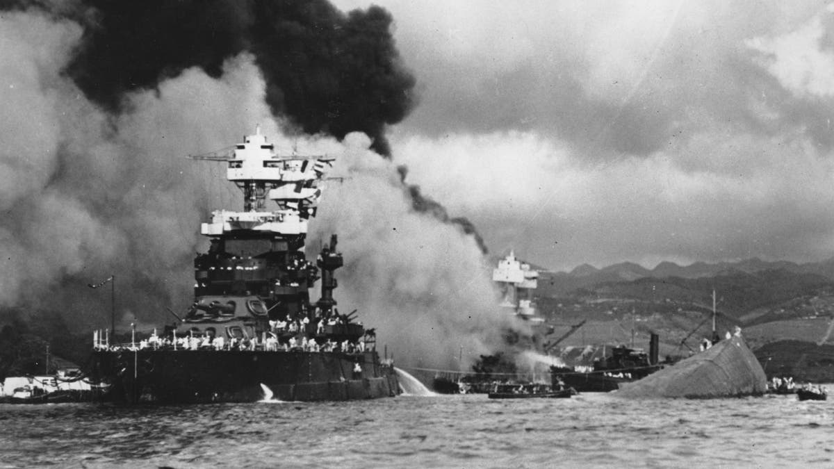 In this Dec. 7, 1941 file photo, part of the hull of the capsized USS Oklahoma is seen at right as the battleship USS West Virginia, center, begins to sink after suffering heavy damage, while the USS Maryland, left, is still afloat in Pearl Harbor, Oahu, Hawaii.?