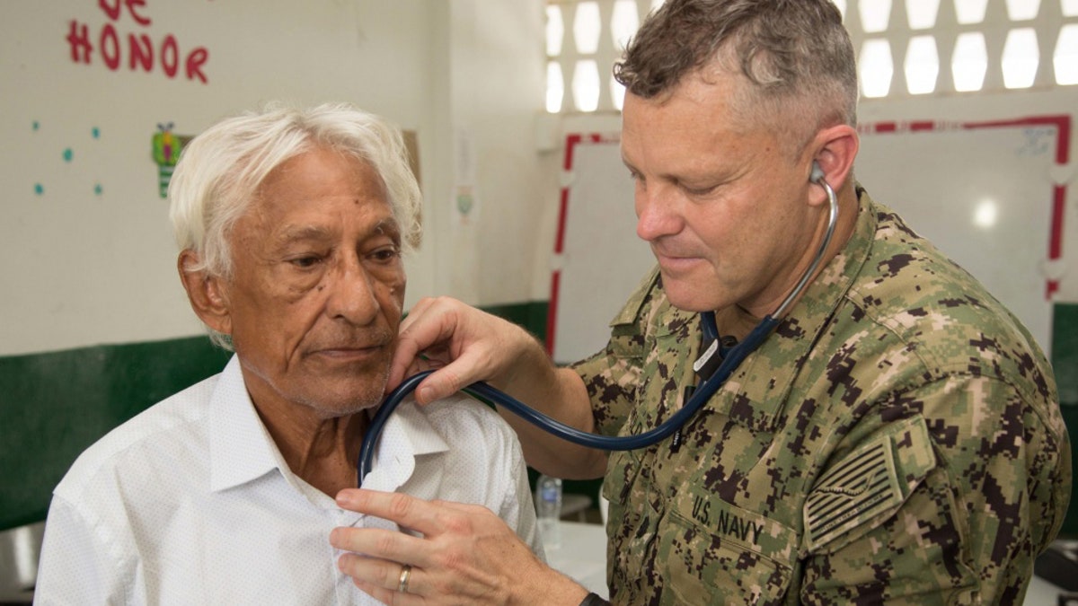 Cmdr. Ryan Griswold, from Madison, Iowa, examines a patient for health issues at one of two medical sites.