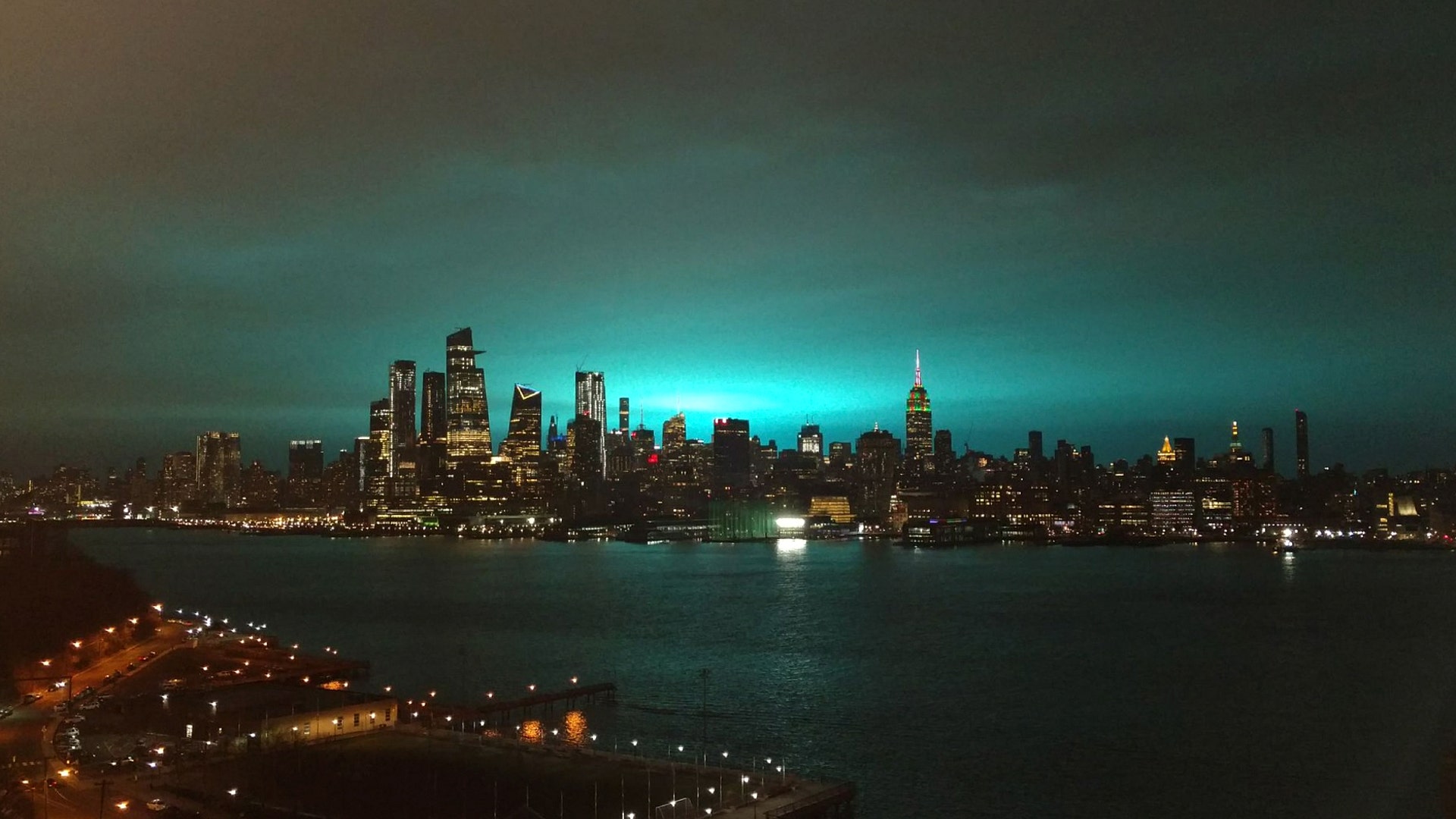 A blue glow lights up the sky behind the skyline of midtown Manhattan after a Con Ed transformer exploded in New York City, Dec. 27, 2018.