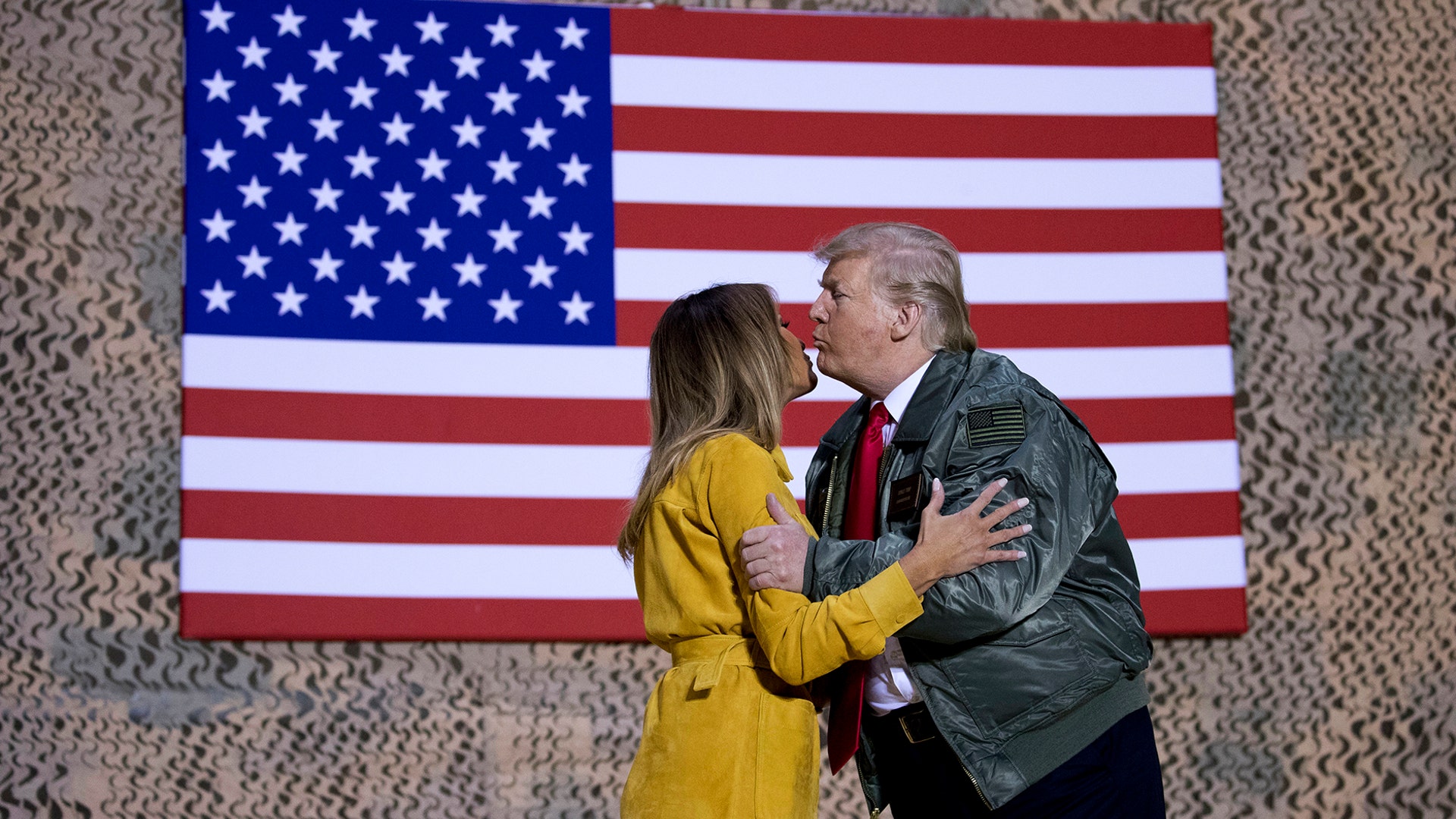 President Donald Trump kisses first lady Melania Trump during a hanger rally at Al Asad Air Base, Iraq, Dec. 26, 2018. 