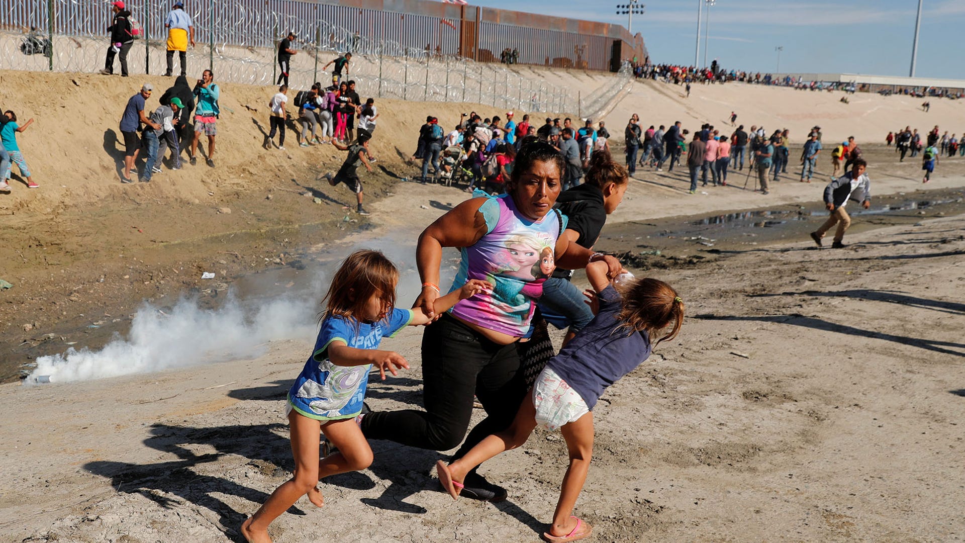 A migrant family, part of a caravan of thousands traveling from Central America en route to the United States, run from tear gas in front of the border wall between the U.S. and Mexico in Tijuana, Mexico November 25, 2018. 