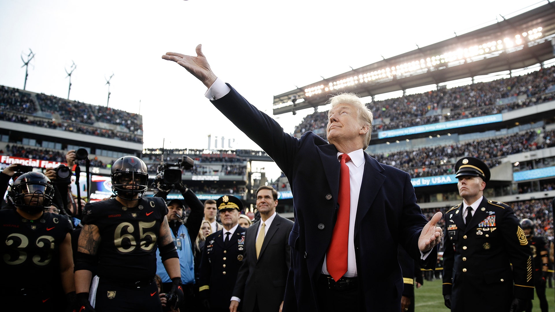 President Donald Trump tosses the coin before the Army-Navy NCAA college football game in Philadelphia, Dec. 8, 2018. 
