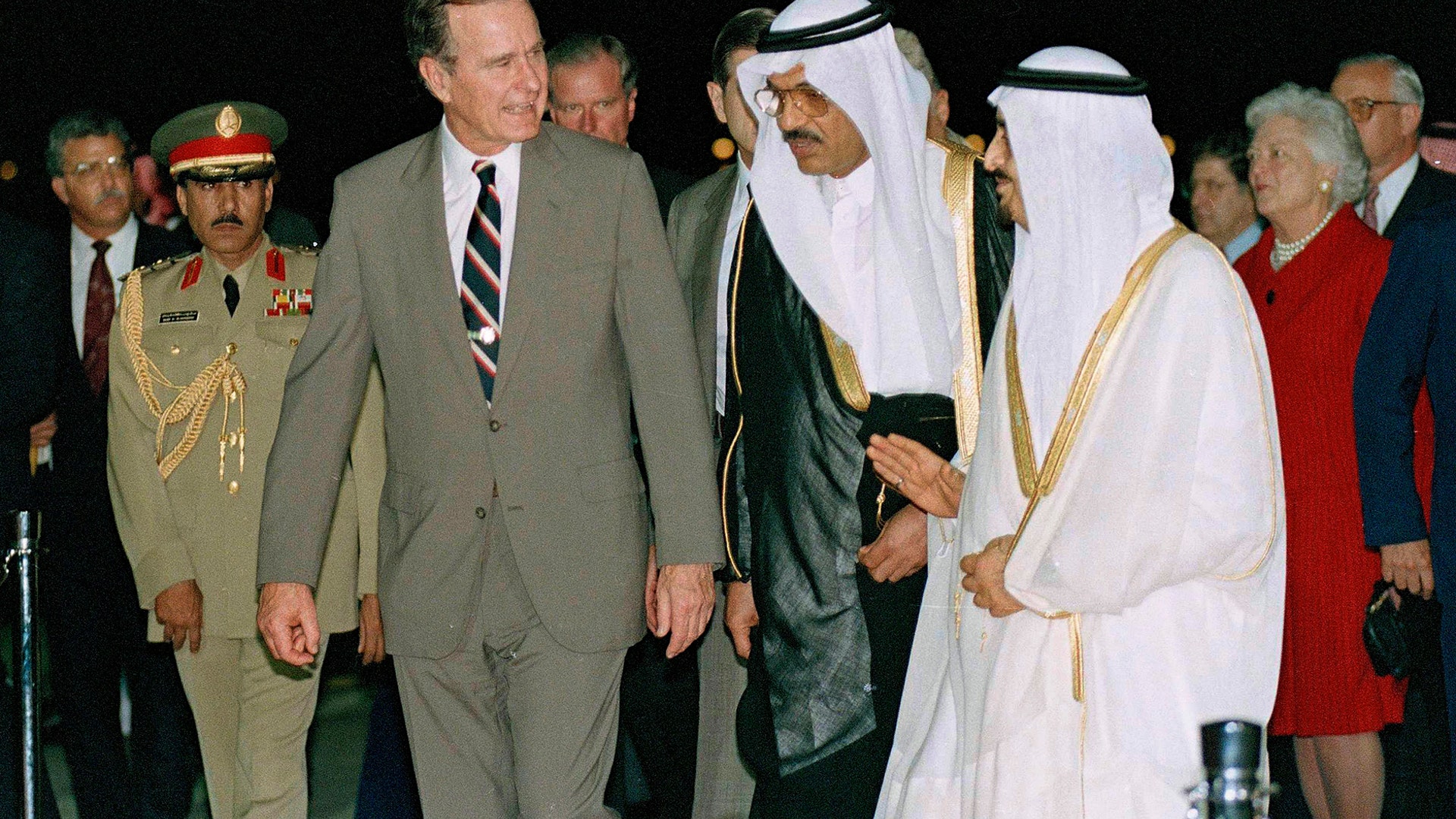 In this Nov. 21, 1990 file photo, President George H.W. Bush is greeted by King Fahd as he arrives in Saudi Arabia. At right is first lady Barbara Bush. At center is an interpreter. 