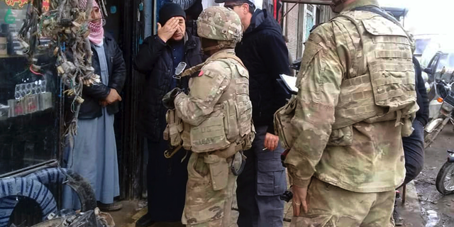 This photo released on the Facebook page of the Military Council of Manbij City, shows U.S. troops based around the Syrian town of Manbij speaking with residents, in northern Syria, Sunday, Dec. 23, 2018. (The Military Council of Manbij City via AP)