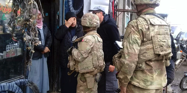 This photo released on the Facebook page of the Military Council of Manbij City, shows U.S. troops based around the Syrian town of Manbij speaking with residents, in northern Syria, Sunday, Dec. 23, 2018. (The Military Council of Manbij City via AP)