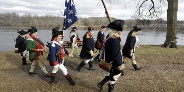Re-enactor John Godzieba, right, portrays Gen. George Washington as he leads others along the banks of the Delaware River, Tuesday Dec. 25, 2018 in Washington Crossing, Pa.