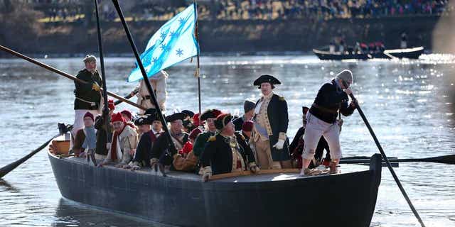 In this Dec. 25, 2016 file photo, John Godzieba, as Gen. George Washington, second right, stands in a boat during a re-enactment of Washington's daring Christmas 1776 crossing of the Delaware River in Washington Crossing, Pa.