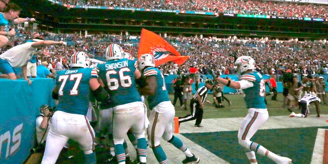 The Miami Dolphins celebrate with running back Kenyan Drake after he scored the winning touchdown during fourth quarter of an NFL football game against the New England Patriots Sunday.