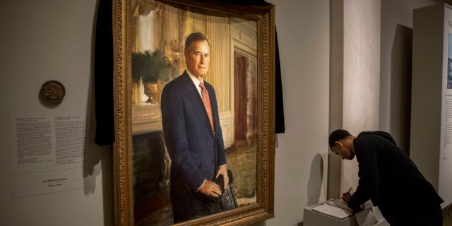 The official portrait of former President George H.W. Bush is draped in black cloth at the National Portrait Gallery before he will lie in state at the Capitol building this week.