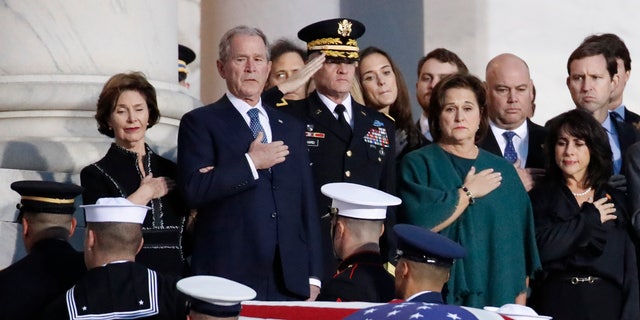 Former President George W. Bush and other family members watch as the flag-draped casket of former President George H.W. Bush is carried by a joint services military honor guard to lie in state in the Rotunda of the U.S. Capitol.