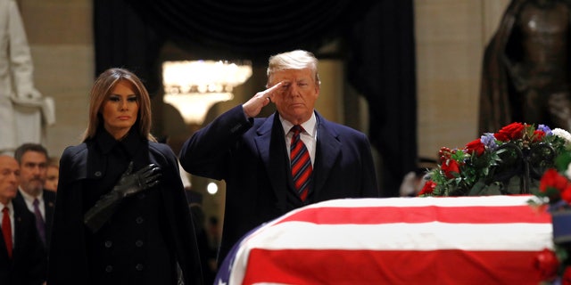 President Donald Trump salutes alongside first lady Melania Trump in front of the flag-draped casket of former President George H.W. Bush in the Capitol Rotunda.