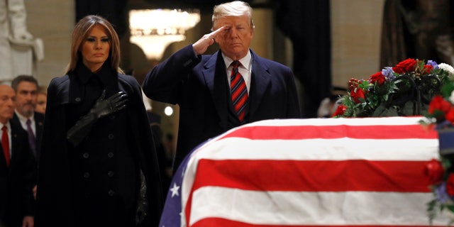 President Donald Trump salutes alongside first lady Melania Trump in front of the flag-draped casket of former President George H.W. Bush in the Capitol Rotunda.