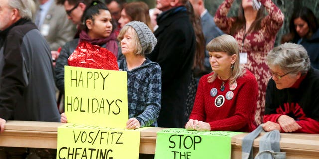   Protesters Peppi Elder, left, and Christine Taylor hold up placards at the Christmas Tree Lighting Ceremony in the Chapter Capital, Tuesday, December 4, 2018 in Madison, Wisconsin . The Senate and Assembly will send dozens of amendments to state legislation to Governor Scott Walker's office. (Steve Apps / Wisconsin State Diary via AP) 