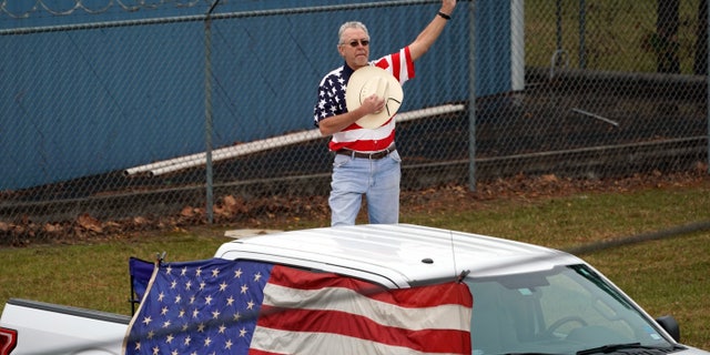 A man makes a patriotic display as the train carrying the casket of former President George H.W. Bush passes.