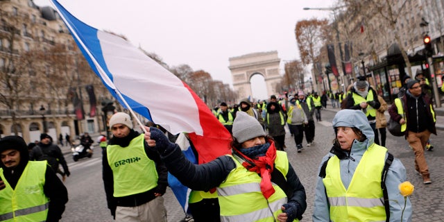 Demonstrators wearing yellow vests walk down the Champs-Elysees avenue, Saturday, Dec. 15, 2018 in Paris. A strong police presence has deployed in Paris before planned demonstrations by the "yellow vest" protesters, with authorities repeating calls for calm after previous violent protests and rioting.