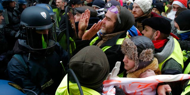 Demonstrators face riot police officers during a protest Saturday, Dec. 15, 2018 in Paris. (AP Photo/Michel Euler)
