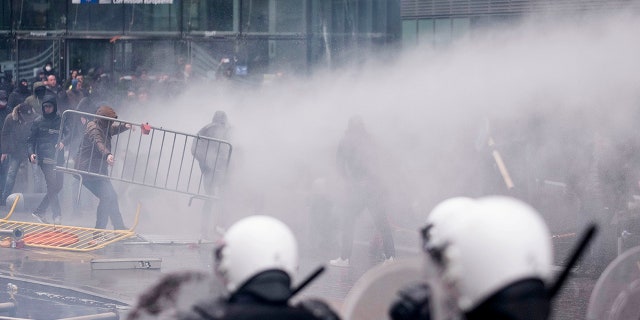Protestors face off against the police during an anti-migrant demonstration outside of EU headquarters in Brussels, Sunday, Dec. 16, 2018. Police used tear gas and water cannons to disperse demonstrators around the European Union headquarters at the end of a march to protest the adoption of a U.N. migration pact. (AP Photo)