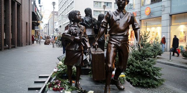 People pass a commemorative memorial statue to perpetuating the memory of the 'Kindertransport' (children transport) near Friedrichstrasse train station in central in Berlin, Germany, Monday, Dec. 17, 2018. Germany has agreed to one-time payments for survivors, primarily Jews, who were evacuated from Nazi Germany as children, many of whom never saw their parents again. (AP Photo/Markus Schreiber)