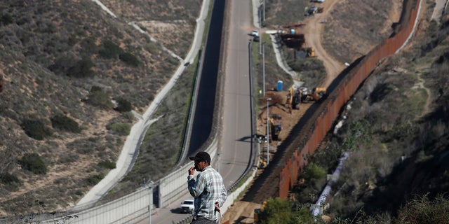 A man looks out at the U.S. border where workers are replacing parts of the U.S. border wall for a higher one, in Tijuana, Mexico, Dec. 19, 2018. (Associated Press)