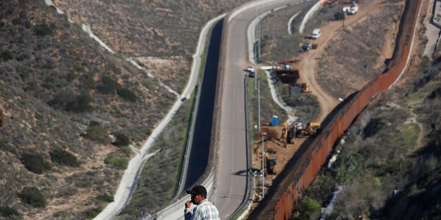 A man looks out at the U.S. border where workers are replacing parts of the U.S. border wall for a higher one, in Tijuana, Mexico, Wednesday, Dec. 19, 2018. Workers are reinforcing and changing pieces of the wall where migrants seeking to reach the U.S. have been crossing. (AP Photo/Moises Castillo)