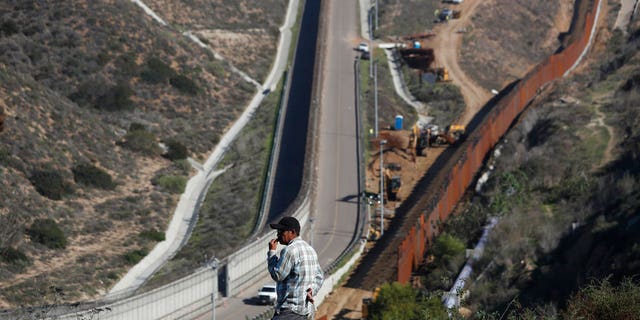 A man looks out at the U.S. border where workers are replacing parts of the U.S. border wall for a higher one, in Tijuana, Mexico, Wednesday, Dec. 19, 2018. Workers are reinforcing and changing pieces of the wall where migrants seeking to reach the U.S. have been crossing. (AP Photo/Moises Castillo)