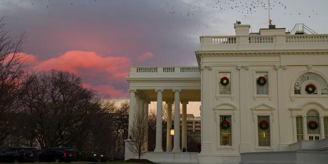 The setting sun illuminates clouds behind the White House during a partial federal shutdown, Saturday, Dec. 22, 2018, in Washington. The partial federal shutdown was expected to drag into Christmas as President Donald Trump and congressional leaders remained stuck in a standoff over his border wall with Mexico. (AP Photo/Alex Brandon)