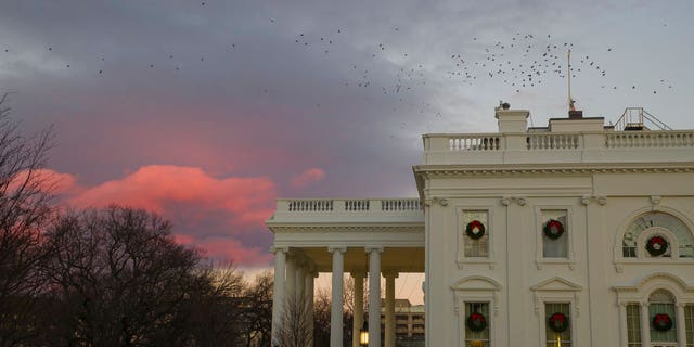 The setting sun illuminates clouds behind the White House during a partial federal shutdown, Saturday, Dec. 22, 2018, in Washington. The partial federal shutdown was expected to drag into Christmas as President Donald Trump and congressional leaders remained stuck in a standoff over his border wall with Mexico. (AP Photo/Alex Brandon)