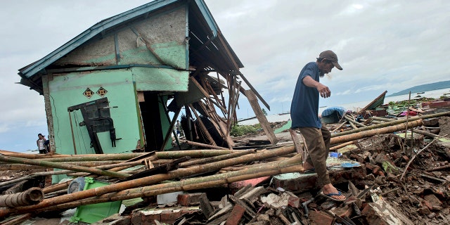 A man makes his way past a house badly damaged by a tsunami in Sumur, Indonesia, Monday, Dec. 24, 2018. Doctors worked to save injured victims while hundreds of military and volunteers scoured debris-strewn beaches in search of survivors Monday after a deadly tsunami gushed ashore without warning on Indonesian islands on a busy holiday weekend. (AP Photo/Fauzy Chaniago)