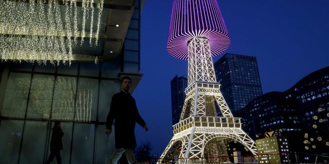 People pass by a replica of the Eiffel Tower covered with a lamp shade outside a shopping mall set up ahead of Christmas in Beijing, China, Tuesday, Nov. 27, 2018. Officials in the northern Chinese city of Langfang have banned decorations this year.